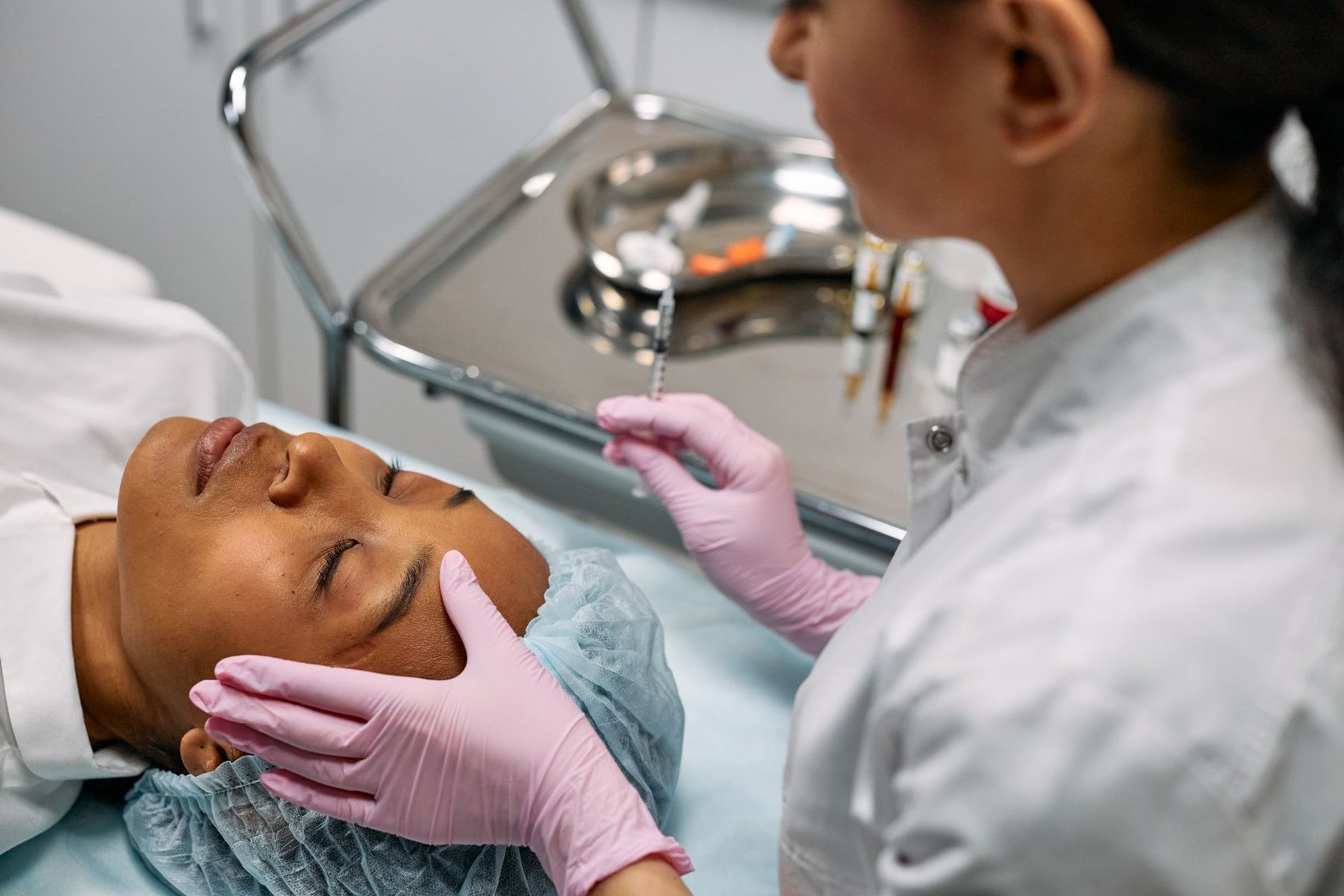 Tratamiento facial con guantes rosados en camilla